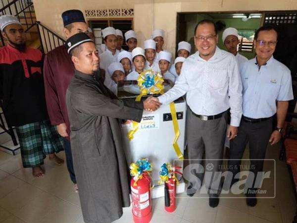 Ahmad Amzad (dua dari kanan) menyerahkan sumbangan kepada wakil pusat tahfiz hari ini.