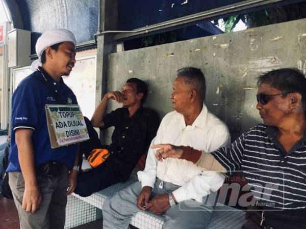 Mohd Hasyir bersama pelanggan yang mendapatkan khidmat pembayaran bil utiliti dan kad tambah nilai di hadapan masjid negeri.