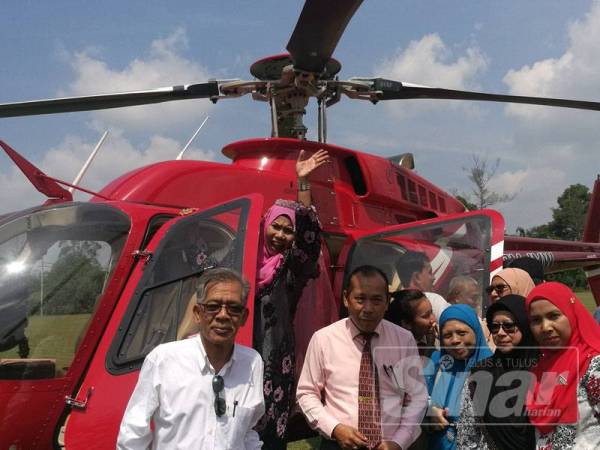 Zahara melambai tangan kepada rakan-rakan dan murid sebelum menaiki helikopter sambil diperhatikan Mokhtar (berdiri dari kiri).