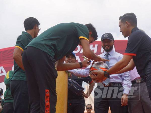 Mohd Fadzrul menandatangani bola untuk dihadiahkan kepada penyokong Hijau Kuning pada Majlis Perarakan dan Sambutan Kemenangan Shoppe Piala FA 2019 di Dataran Wisma Darul Aman, di sini hari ini.