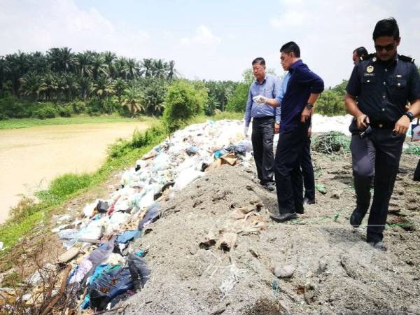 Kok Yew (kiri) ketika membuat pemantauan di lokasi tapak pelupusan sampah di Kampung Kemumbung, Sidam Kiri Jumaat lalu.