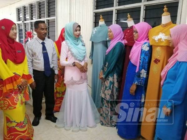 Faridah (tiga dari kiri) beramah-mesra dengan peserta jahitan sewaktu Majlis Penyerahan Kit Peralatan Kursus Quick Win Pastri dan Jahitan Variasi Jubah kepada 30 peserta di Pejabat Kemas Parlimen Hulu Terengganu semalam.