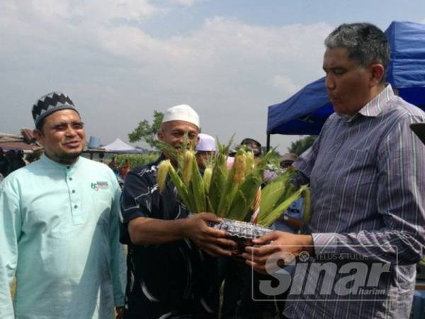 Mohd Sallehhuddin (kanan) menerima cenderamata daripada ketua projek tanaman jagung selepas melawat kawasan Ladang Jagung Paloh di Tanah Merah hari ini.