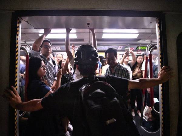 Seorang penunjuk perasaan menghadang pintu tren MTR di stesen Fortress Hill, Hong Kong. - Foto AFP
