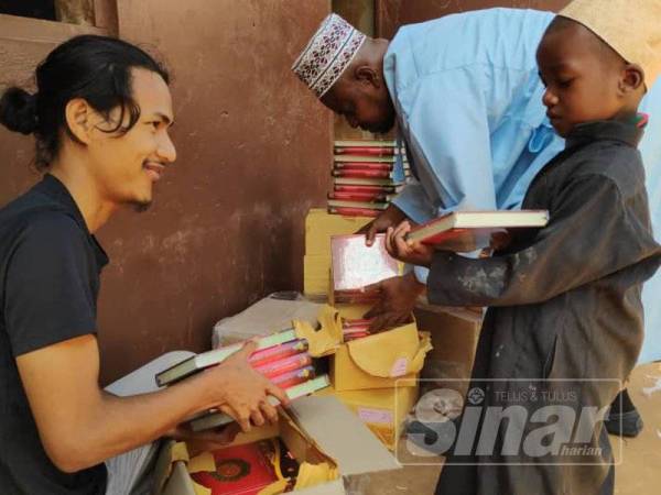 Sukarelawan Salam, Muhammad Firdaus Al Musanna sedang mengagihkan naskhah al-Quran kepada salah seorang kanak-kanak di Madrasah Hashimia Kizimkazi.