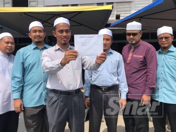 
Mohd Ariff menunjukkan surat jemputan di bangunan tertera tanda DAP negeri di Kampung Bunut Payong hari ini.