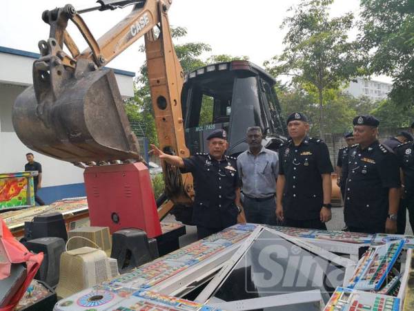 Mohd Said (kiri) menunjukkan mesin judi siber yang telah dimusnahkan.