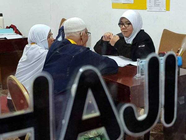 Petugas Pembimbing Ibadah Haji Tanah Suci Roshaini Mat Kasa (kanan) menemu bual pasangan suami isteri Che Hamzah Ngah Ismail, 80, (tengah) dan Naemah Abu Sharif, 75, untuk proses saringan program Jemaah Haji Warga Emas hari ini. - Foto Bernama