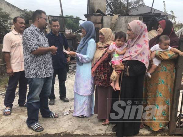 Mohd Sukirman (dua, kiri) menyampaikan sumbangan kepada wakil mangsa kebakaran di Kampung Dusun Jalan Bayam hari ini.