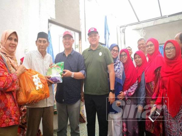 Mat Nadzari (tiga dari kiri) bersama Rizam (empat dari kiri) menyampaikan sumbangan kepada salah seorang mangsa ribut di Sabak Bernam, semalam.