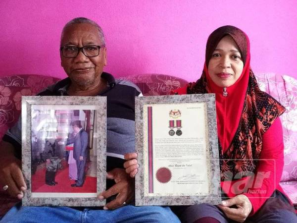 Abdul Razak(kiri) dan isteri, Zaiton Darham menunjukkan gambar kenangan sewaktu dia menerima pingat penghargaan Pingat Jasa Malaysia(PJM) oleh Menteri Pertahanan ketika itu, Datuk Seri Hishamuddin Tun Hussien pada tahun 2017.