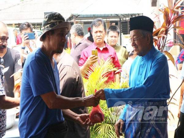 Mahathir menyampaikan daging korban kepada penduduk yang hadir pada majlis ramah mesra dalam Parlimen Langkawi di sini hari ini.