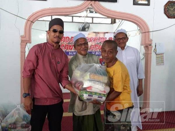 Abd Nasir (tengah) menyampaikan sumbangan kepada salah seorang penerima di Surau Ubidiah Kampung Padang Che Mas sempena Aidiladha, Ahad lalu.