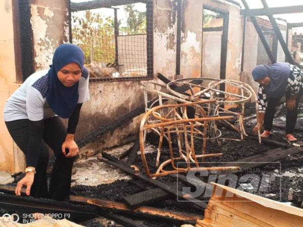 Nur Fazira (kiri) bersama ibunya memeriksa sisa kebakaran di rumah mereka di Kuala Bagan Tiang, Parit Buntar.