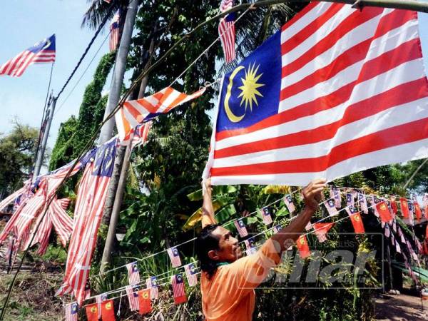 Mohd Salleh membetulkan Jalur Gemilang yang dipasang di hadapan rumahnya di Kampung Pinang, Alor Setar semalam.