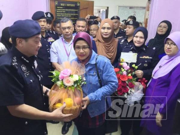 Mazlan (kiri) menyampaikan buah tangan kepada isteri Mohd Zamri, Azini Mamat ketika melawat mangsa di HUSM hari ini.