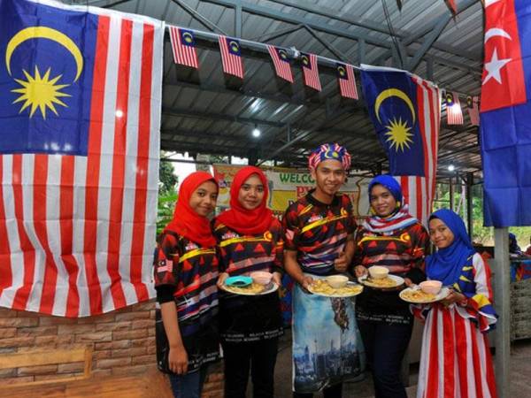 Setiap tahun sejak empat tahun lalu, seorang peniaga roti canai yang juga lebih dikenali sebagai 'roti terbang' oleh penduduk setempat, Mohd Suffian Md Ali, 36 (tengah) tidak akan melepaskan peluang untuk menzahirkan rasa kecintaannya pada negara. Foto: BERNAMA