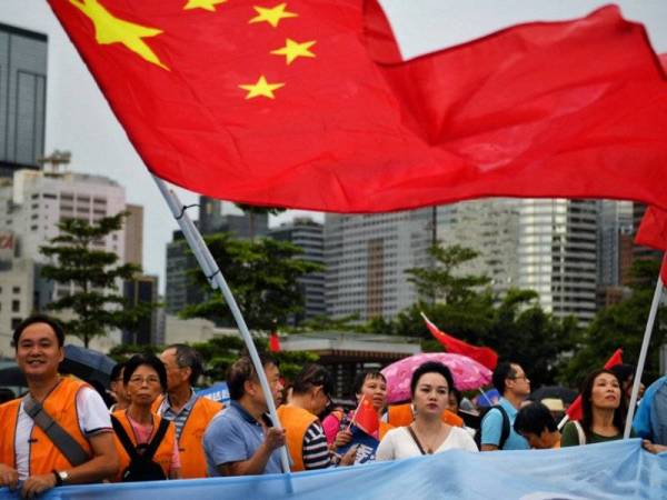 Penyokong proBeijing mengibarkan bendera China ketika himpunan di Tamar Park Hong Kong hari ini. - Foto AFP