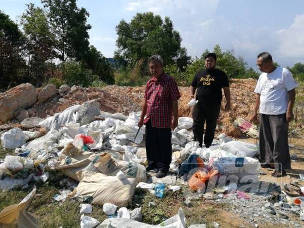 Othman (kiri) dan Shahfudin (tengah) bersama seorang lagi penduduk meninjau lokasi pembuangan sisa mencurigakan di kampung mereka.