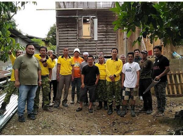 Khairul Hakimi (empat dari kanan) bersama Mohd Affandi (kanan), Pemuda PH, Rela dan penduduk kampung yang hadir untuk membaik pulih rumahnya secara bergotong-royong di sini kelmarin.