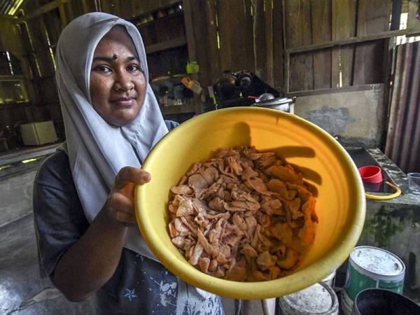 Suri rumah, Siti Hamidah Abdul Aziz, 32, menunjukkan kulit ayam yang belum digoreng untuk dijadikan hidangan mereka sekeluarga yang diambil dari kantin sebuah sekolah berhampiran rumahnya di Kampung Tengah hari ini. - Foto Bernama