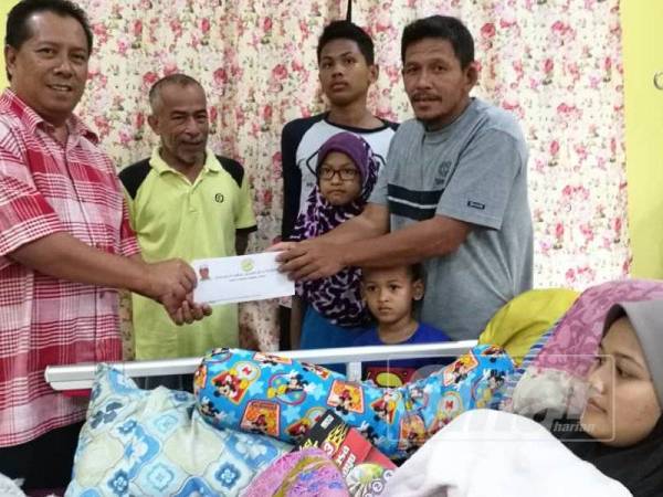 Zulkepli (kiri) menyampaikan sumbangan kepada Anuar (kanan) di rumah Jamilah di Kampung Batu Balai Isnin lalu.