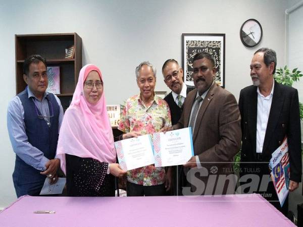 Marhaini (dua kari kiri) dan Mohamed Hanim (dua dari kanan) bertukar-tukar dokumen yang ditandatangani sambil disaksikan Muhammad Nasir (tiga dari kiri). - Foto ASRIL ASWANDI SHUKOR