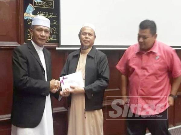 Mohd Zain menerima hadiah kemenangan yang disampaikan Imam Tua Masjid Mahmoodi, Bachok, Baharin Yusoff (tengah).