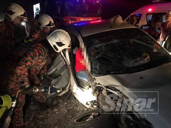 Anggota bomba dan penyelamat membantu mengeluarkan mangsa dari kereta yang remuk.