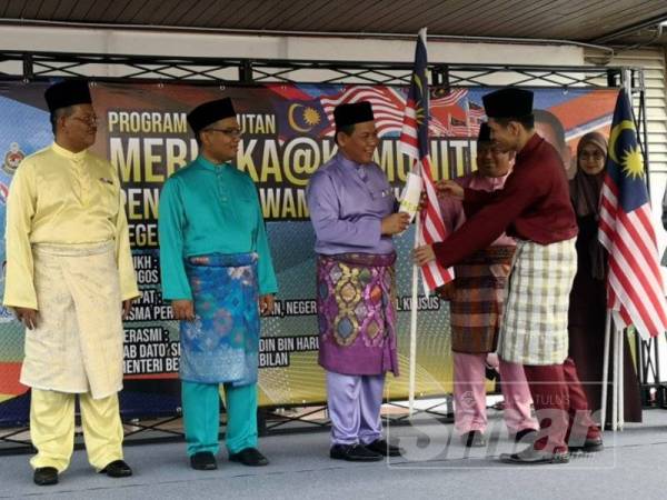 Aminuddin (tiga dari kiri) menyampaikan Jalur Gemilang kepada wakil jabatan sempena Bulan Kebangsaan.