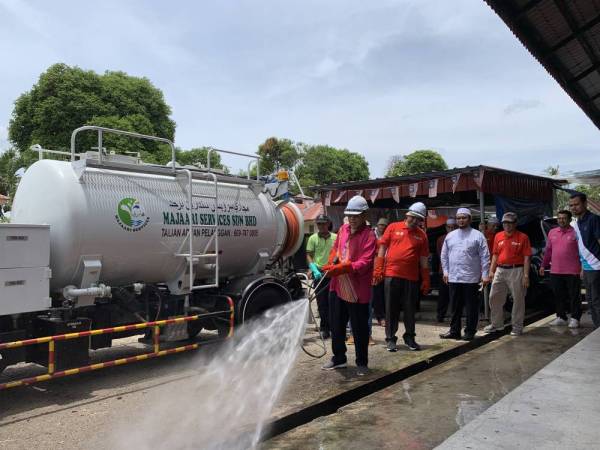 Ahmad menyembur air di Pasar Besar Kedai Buloh sebagai gimik perasmian program tersebut hari ini.