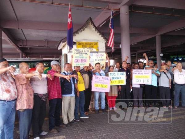 Ahli-ahli PDMK yang membantah pelaksanaan Gojek di Hentian Teksi Kluang di sini hari ini.