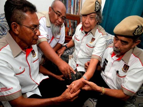 Baharuddin (dua dari kanan) menunjukkan kesan tangan kirinya yang patah kepada rakan-rakannya ketika dalam Operasi Bamboo II di sempadan Malaysia-Thailand pada tahun 1978 bagi membasmi ancaman Parti Komunis Malaya ketika ditemu bual di kediamannya di Tambun, semalam. - Foto Bernama