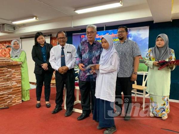 Hassan (tiga dari kiri) bersama Jasni (dua dari kiri) menyampaikan sumbangan alat tulis kepada murid tahun enam pada majlis pelancaran Kempen Kesedaran Mengenai Pengetahuan Keselamatan Diri di Pasir Gudang di SK Taman Megah Ria hari ini.