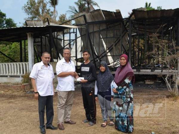 Mohd Razali (dua dari kiri) menyampaikan sumbangan kepada Muhd Afiq Firdaus.