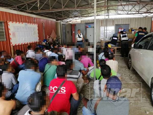 Sebahagian daripada PATI yang ditahan sedang menunggu untuk diperiksa oleh anggota Imigresen di lokasi serbuan di Kuala Nerus kelmarin.