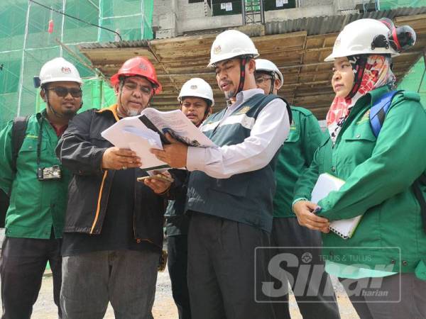 Izani (dua dari kanan) melihat pelan projek ketika melawat sebuah tapak projek pembinaan di Seremban 2.