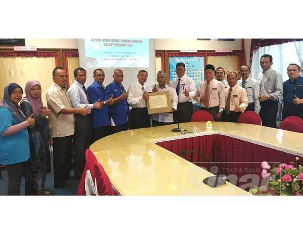 Abd Rahim (lapan dari kanan) mewakili Mustapa menyerahkan set alat tulis kepada guru- guru besar yang mewakili calon UPSR Parlimen Jeli di sini semalam.