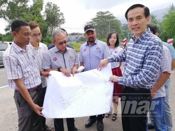 Chong Sin menunjukkan lakaran kerja-kerja pelebaran jambatan dan jalan di Jalan P Srinivasan, Kluang.