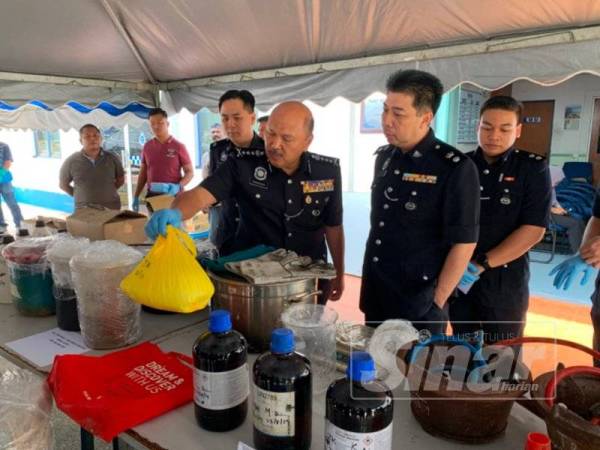 Kamarudin (tiga dari kanan) menunjukkan bahan mentah untuk memproses dadah yang dirampas dalam operasi.