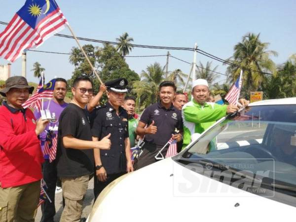 Maliaman (kanan) melekatkan Jalur Gemilang pada kenderaan pengguna jalan raya sewaktu Program Gotong-royong Merdeka di Ajil, Hulu Terengganu.