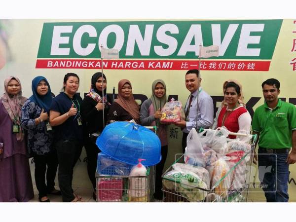 Zamzuri(tiga kanan) menyempurnakan gimik penyerahan sumbangan baucer membeli-belah barangan di Econsave cawangan Parit Buntar bernilai RM1,000 kepada Nur Fazira(empat kanan) di pasaraya itu, Parit Buntar hari ini.