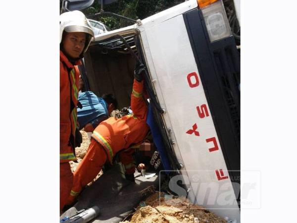 Anggota bomba membantu mengeluarkan pemandu yang tersepit di bahagian pemandu lori.