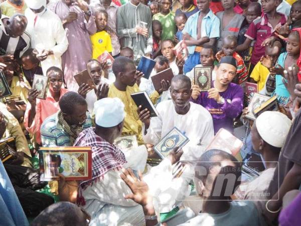 Abdullah (tengah) bersama penduduk Cameroon, Afrika yang gembira menerima wakaf al-Quran.