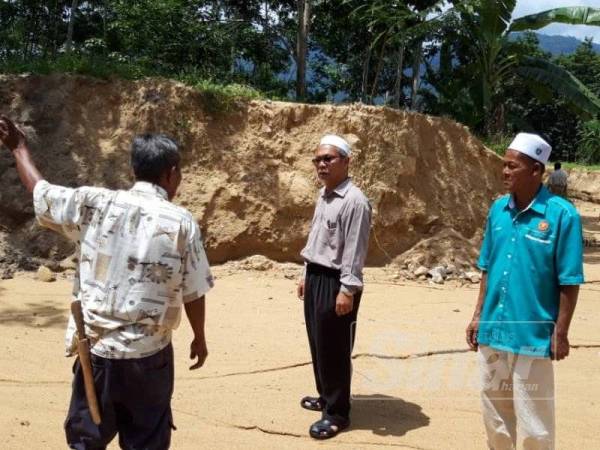 Abd Nasir (tengah) meninjau lokasi timbunan pasir bukit di kawasan kampung penduduk