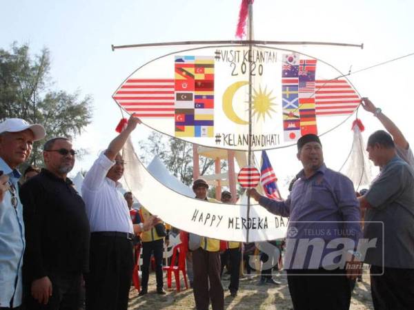 Hassan (kanan) melakukan gimik perasmian dengan menaikkan wau sempena Pesta Wau Antarabangsa kali ke 37 di Pantai Geting.