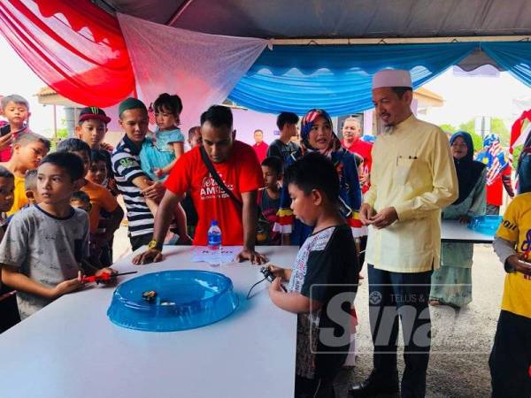 Nik Mohd Abduh (kanan) menyaksikan pertandingan Beyblade di AmKist hari ini.