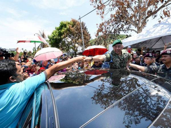 Al-Sultan Abdullah (tengah) berkenan bersalaman dengan penduduk sebelum berangkat pulang selepas melawat dan bertemu mangsa kebakaran rumah di Kampung Otentik, Tanjung Batu Keramat hari ini. - Foto Bernama
