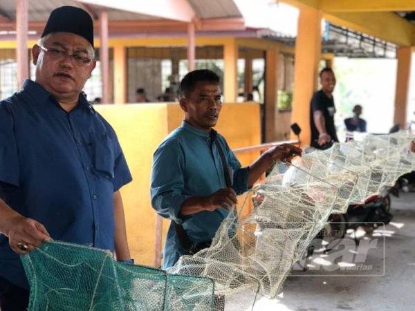 Noh (kiri) bersama-sama nelayan menunjukkan permasalahan dihadapi nelayan kawasan itu berikutan penggunaan bubu naga dalam kalangan warga asing.