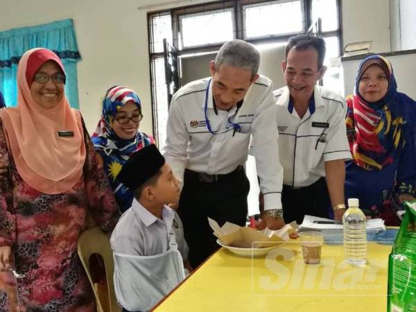 Calon UPSR, Muhammad Aiman Hakim (duduk) mendapat kata-kata semangat daripada Muhd Afandi (tiga dari kanan) dan Guru Besar SK Bunut Susu, Kamarudin Yahya (dua dari kanan).